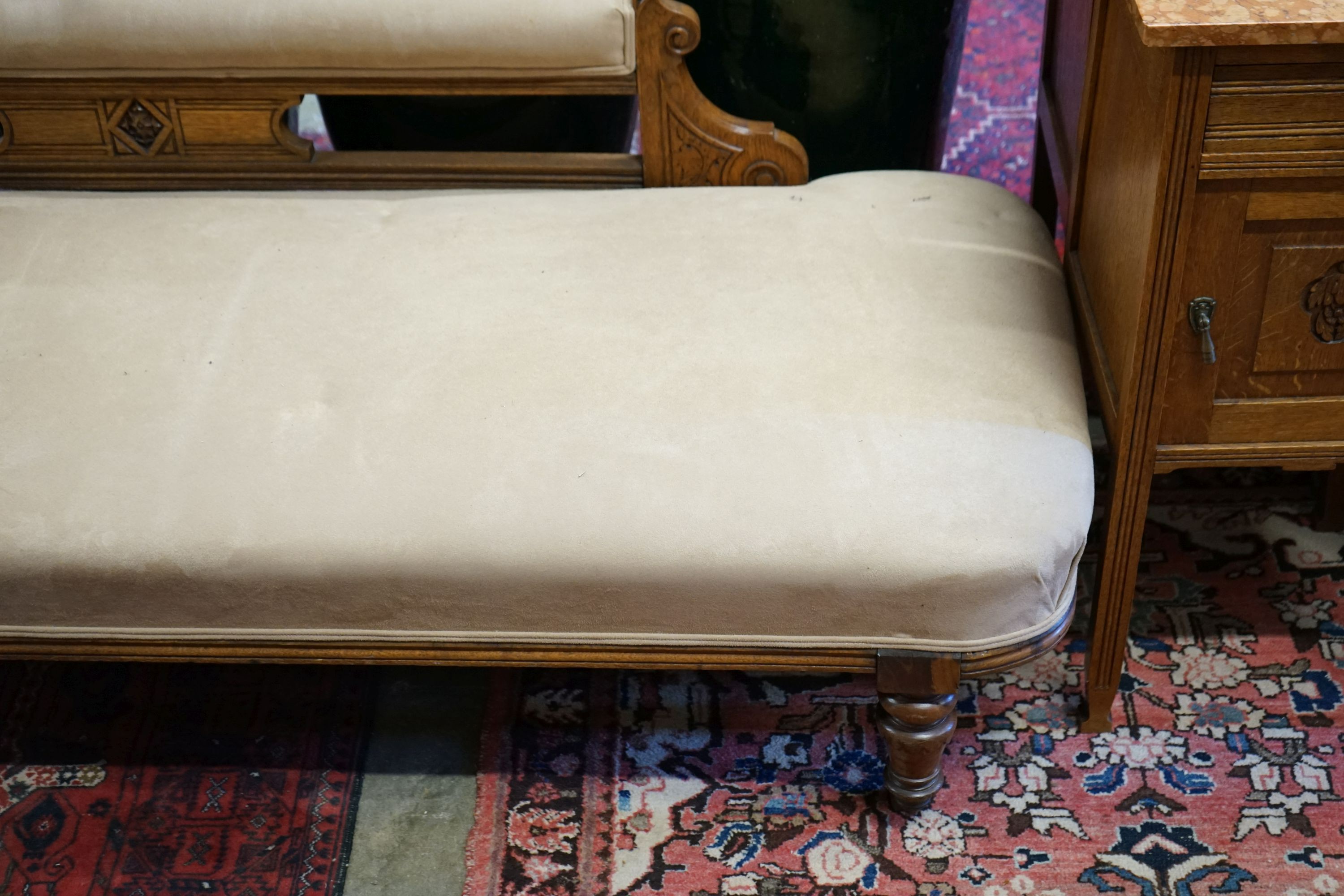 A late Victorian carved oak chaise longue upholstered in fawn suede, length 180cm, depth 70cm, height 79cm